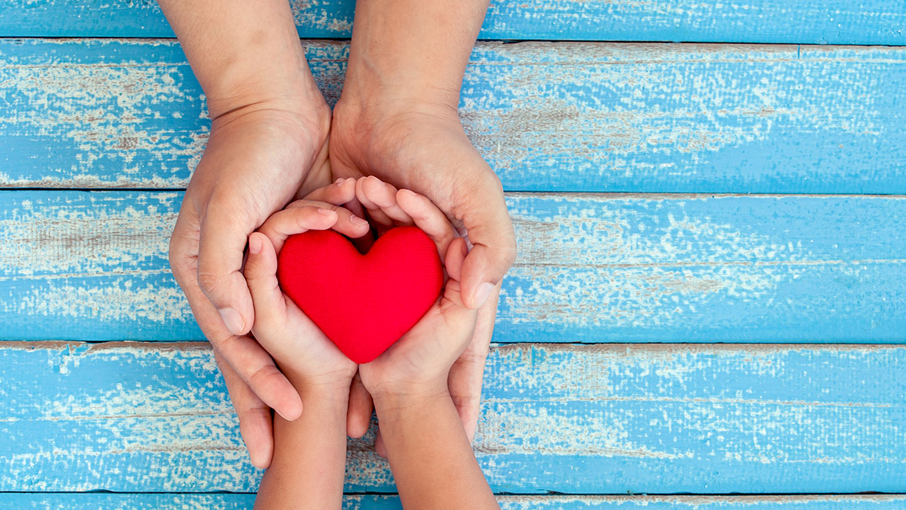Two pair of hands holding heart